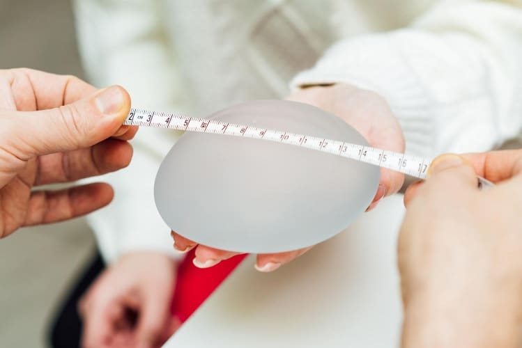 Photo d'une prothèse mammaire qu'on mesure avec un ruban mesureur